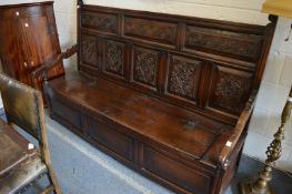 AN 18TH CENTURY OAK SETTLE, with a carved panelled back, curving arms, panelled box seat with hinged