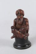 A FINELY CARVED 19TH CENTURY INDIAN WOODEN FIGURE of a turbaned man. 11cms high.