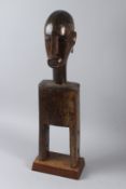 A LARGE TRIBAL CARVED WOOD BUST on a stand. 68cms high.