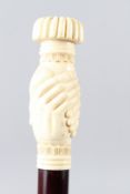 A WALKING STICK with a carved bone handle as a clenched fist. 92cms long.