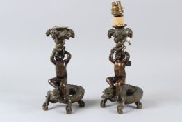 A PAIR OF 19TH CENTURY CAST BRONZE CANDLESTICKS, modelled as cherubs seated on crocodiles. 22cms