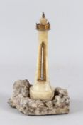 AN EDWARDIAN CARVED ALABASTER LIGHTHOUSE THERMOMETER, mounted on a realistic crystalline rockwork