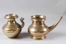 TWO 19TH CENTURY INDIAN BRASS, CIRCULAR EWERS WITH CURVING SPOUTS, one with a mask terminal. 13.5cms
