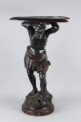 AN UNUSUAL CONTINENTAL CARVED AND EBONISED FIGURAL STAND, modelled as a make semi-nude figure,