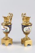 A GOOD PAIR OF ORMOLU AND SEVRES EWER SHAPED CANDLE STANDS, the porcelain bodies painted with
