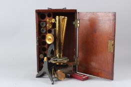 A SWIFT & SON BRASS BINOCULAR MICROSCOPE, with accessories, in a mahogany case.