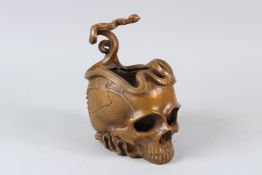 A BRONZE BOWL, modelled as a skull with snakes entwined. 11cms wide.