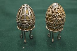 A silver mounted egg box on stand together with a similar decorative egg shaped box with stand.