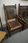 An 18th century oak open armchair with leather upholstered back and seat.