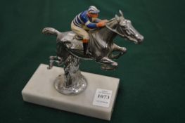 A chrome plated and enamel decorated cast metal model of a leaping horse and jockey, mounted on a