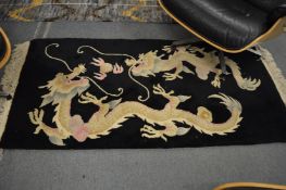 A Chinese rug, black ground decorated with dragons, 154cm x 77cm.