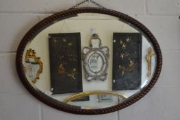 A mahogany framed oval wall mirror with carved frame.