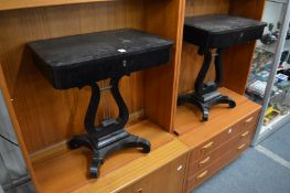 A pair of ebonised work tables with lyre supports.