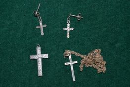 Two silver crucifixes, one with chain and a pair of silver crucifix earrings.