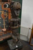 A large carved African wood seated figure on later stand.