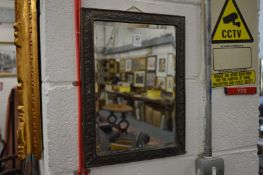 A small mirror with embossed metal frame.
