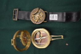 A compass mounted on a wrist strap together with a military style compass.