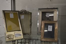A small silver photograph frame and three plated frames.