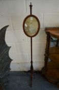 A pair of 19th century mahogany pole screens with small oval plaques, containing embroidered