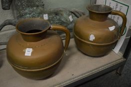 A pair of large metal jugs.