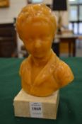 A wax bust of a young boy on a marble base.