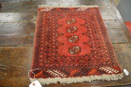 A small Persian bokhara mat, 62cm x 54cm.