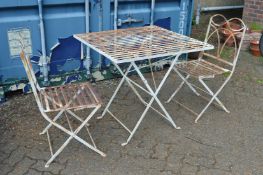 A wrought iron strap work square shaped folding patio table and pair of matching chairs.