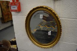 A small gilt framed oval mirror.
