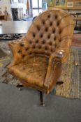 A button upholstered brown leather office swivel armchair.