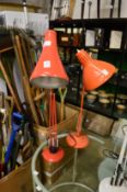 Two orange painted angle poise lamps.