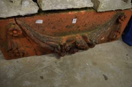 A terracotta door pelmet with floral swags (faults).