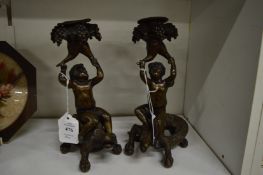 A good pair of bronze candlesticks modelled as cherubs seated on mythological creatures.