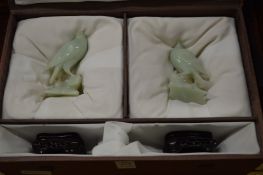 A pair of Chinese carved jade birds on branches with hardwood stands in a fitted case.
