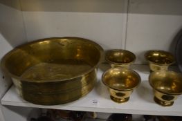 A group of Eastern brass ware to include a large circular bowl and a set of four pedestal bowls.