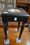 An ebonised stand with painted porcelain inset tile.