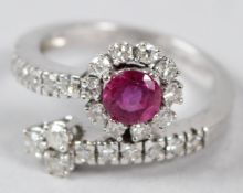 A WHITE METAL, DIAMOND AND RUBY CROSSOVER RING.