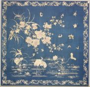 A GOOD 20TH CENTURY SILKWORK PANEL, rich blue ground embroidered with a scene of storks wading in