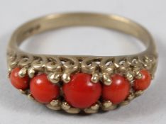 A 9CT GOLD AND CORAL FIVE STONE RING.