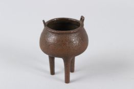 A SMALL BRONZE TWIN-HANDLED CENSER, on three legs. 8cms high.