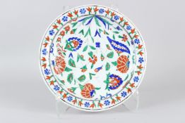 AN OTTOMAN TURKISH IZNIK CIRCULAR DISH, with stylised floral painted decoration. 31cms diameter.