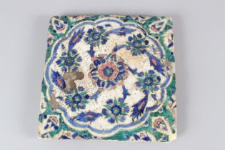 A 19TH CENTURY QAJAR POTTERY TILE, with floral decoration. 27.5cms wide.