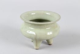 A CHINESE CELADON GLAZED PORCELAIN CENSER, on three feet. 10.5cms diameter.