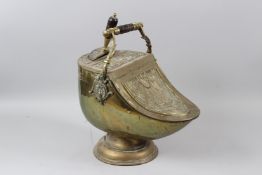 A GOOD VICTORIAN EMBOSSED BRASS HELMET SHAPED COAL SCUTTLE, with hinged cover and matching shovel.