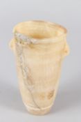 AN EGYPTIAN ALABASTER VESSEL, of tapering cylindrical form, with small lug handles. 14cms high.