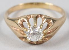 A YELLOW METAL AND CZ SOLITAIRE RING, with openwork mount.