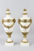 A PAIR OF 20TH CENTURY WHITE MARBLE AND ORMOLU URNS, with basket of fruit finials, rams mask