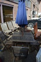 A garden table, set of four folding chairs and a parasol with base.