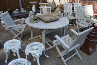A painted circular garden table with three folding armchairs.