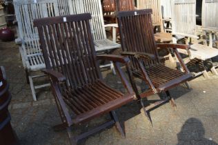 A pair of folding hardwood garden armchairs.