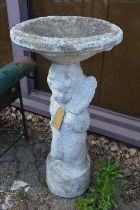 A reconstituted stone figural bird bath.